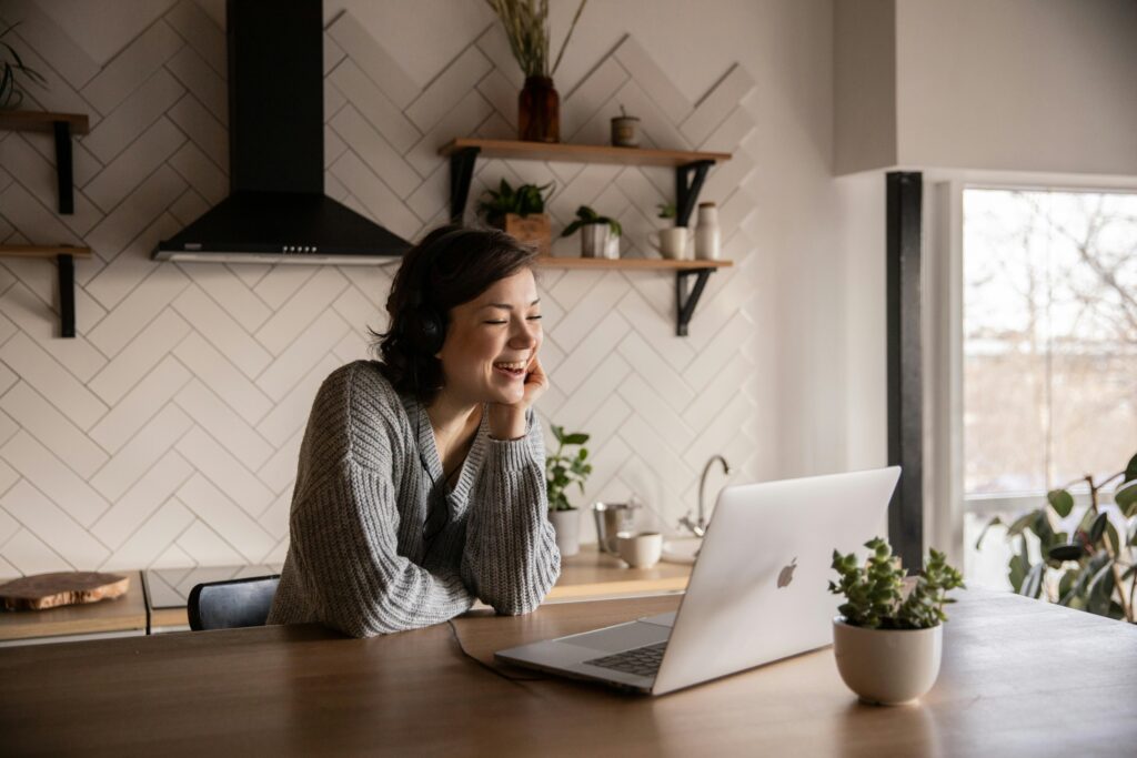 pexels photo 4049992 4049992 Young cheerful female smiling and talking via laptop while sitting at wooden table in cozy kitchen